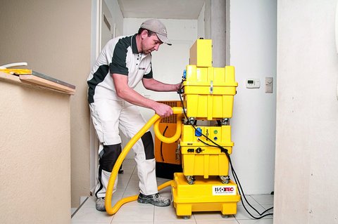 ISOTEC Mitarbeiter bedient gelbes Trocknungsgerät im Raum